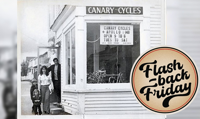 A photo of a cycle shop from the 1970s with a man and woman and 2 young children standing in the entrance, looking at the camera 