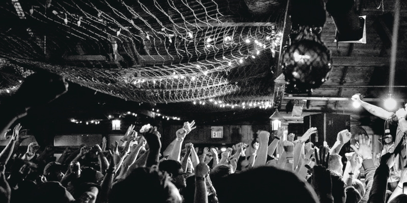 Interior of a club (the Shore Club) with concert goers—arms in the air—enjoying the music