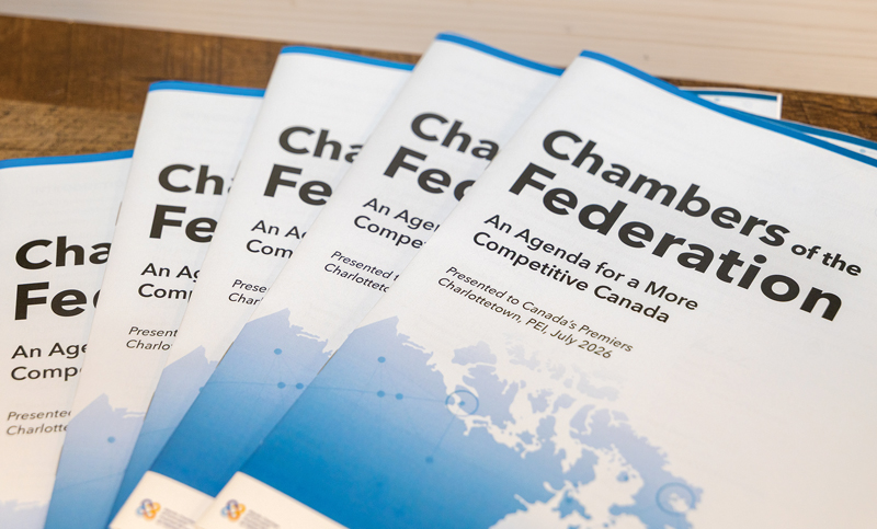 there is a stack of documents fanned out on a desk, and the cover says "Chambers of the Federation, An Agenda for a More Competitive Canada, Presented to Canada's Premiers, Charlottetown, PEI, July 2026